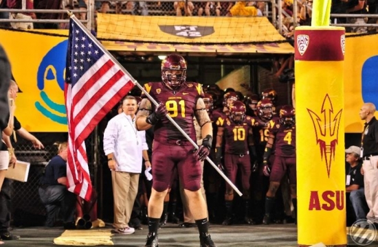 Jake Sheffield leads the team out of Tillman Tunnel with the American flag.